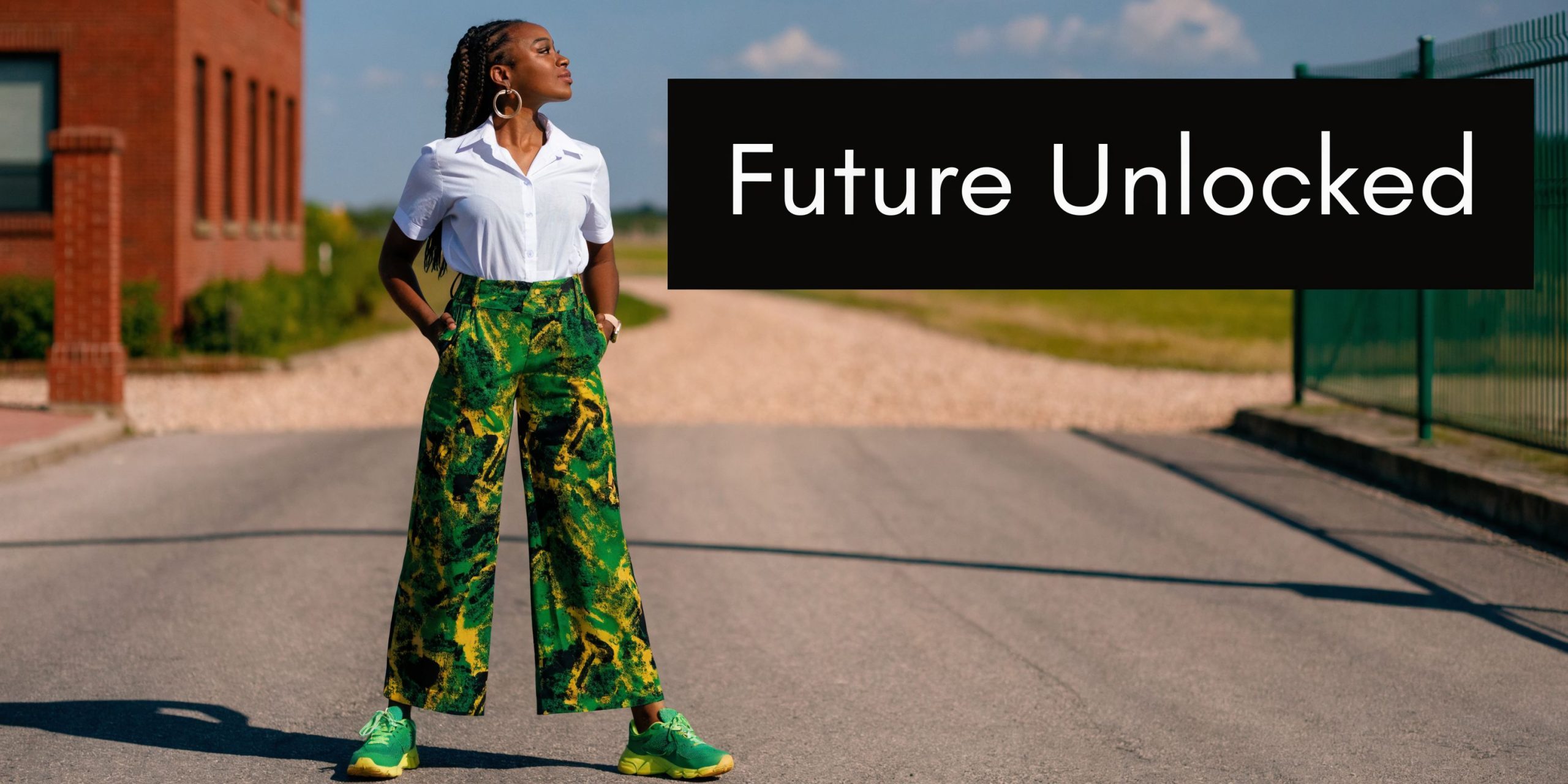 A confident woman wearing a white shirt and patterned green pants standing outside on an asphalt road.