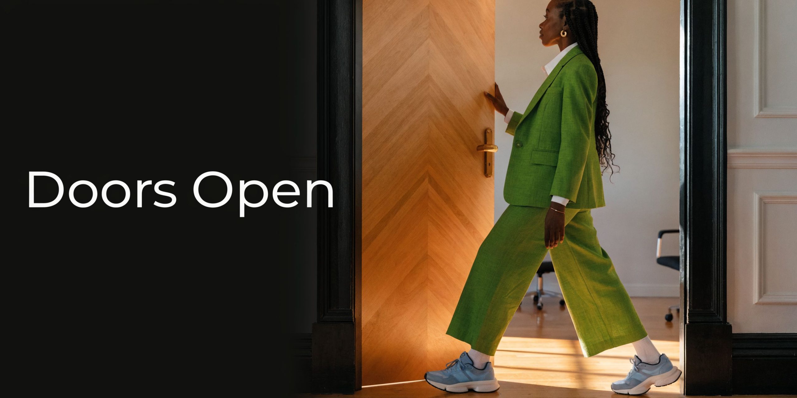 A professional woman in a green suit walks through an open office door toward opportunity.