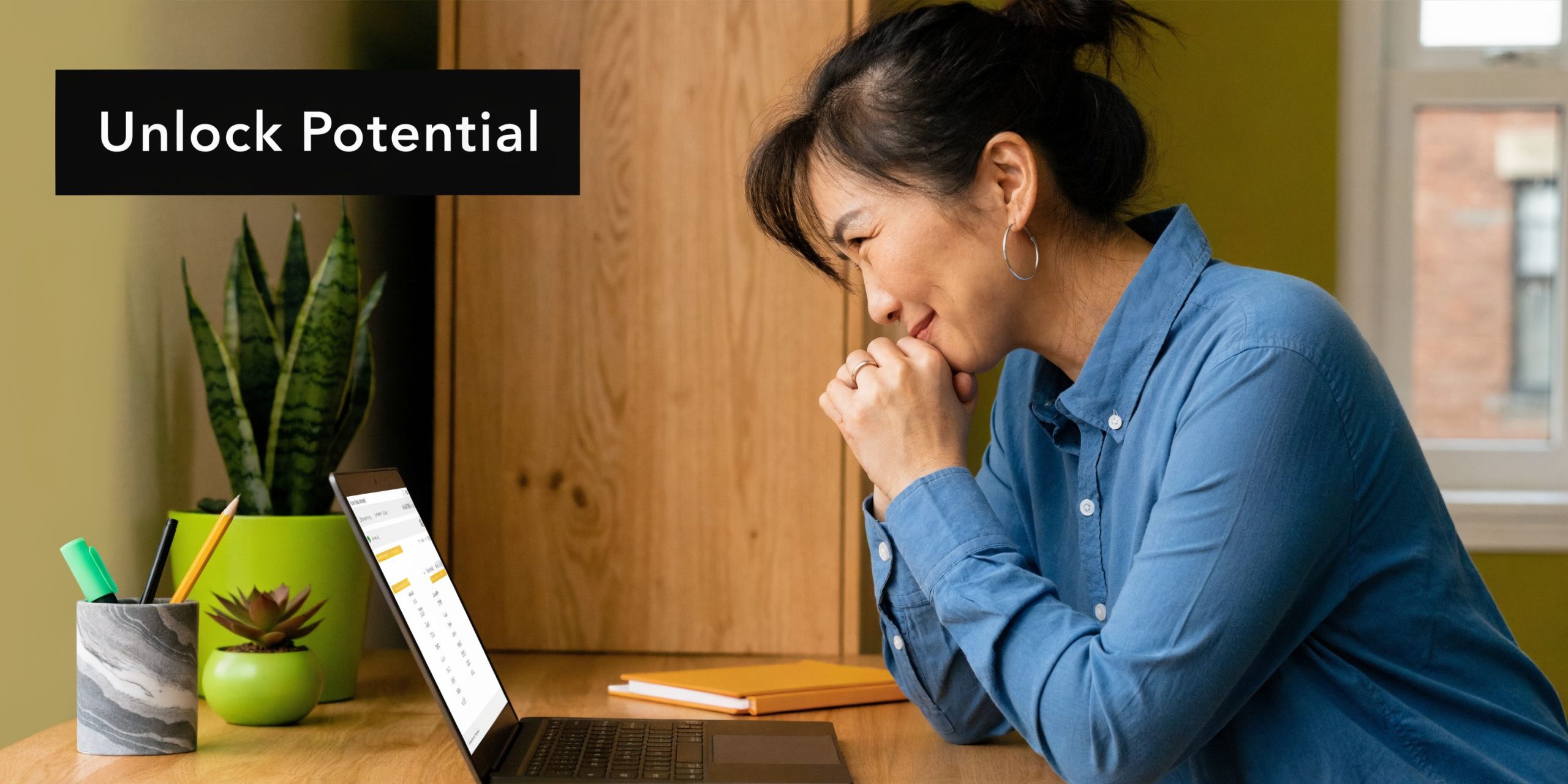 A woman smiling while studying for her maths A level online using a laptop at home.