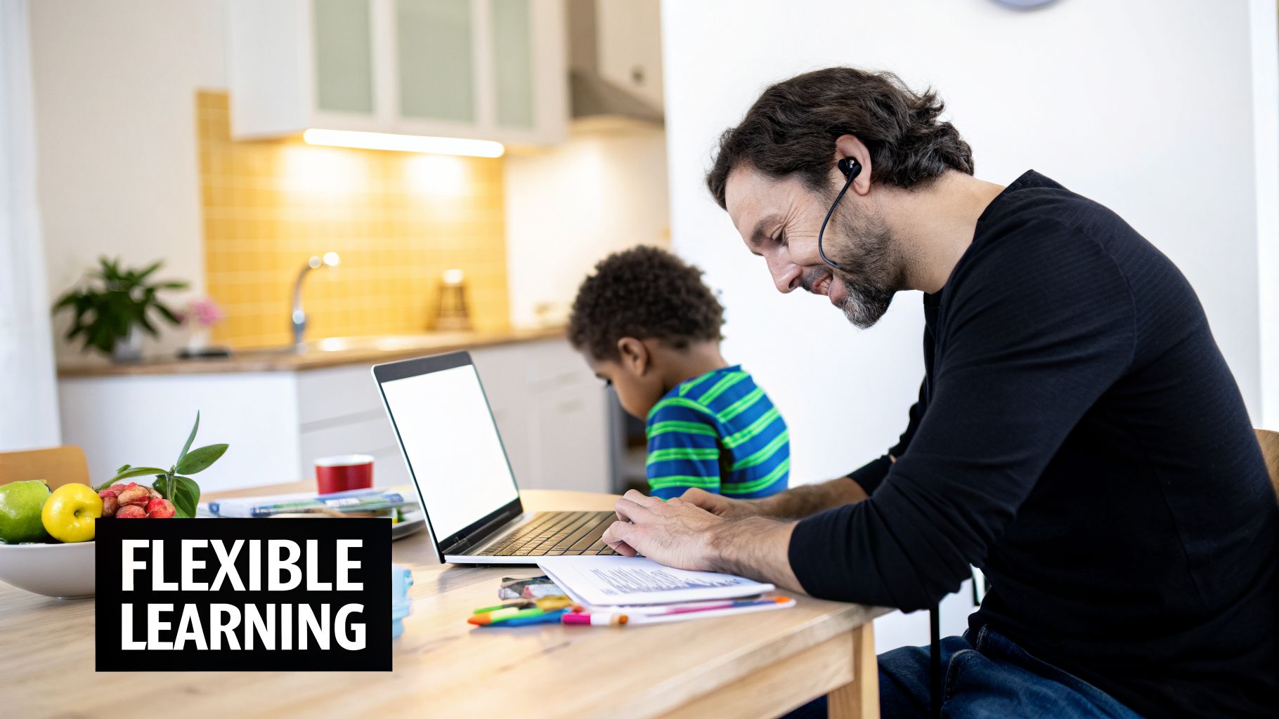 A man wearing an earphone smiles while working on a laptop at a kitchen table, with a child and "FLEXIBLE LEARNING" text.