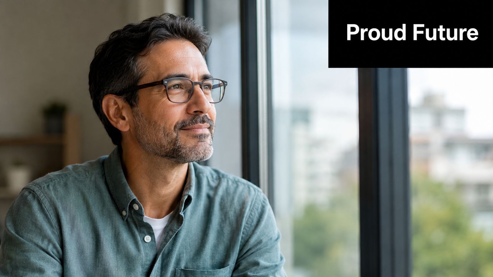 A middle-aged man wearing glasses looks thoughtfully out a bright window with a proud expression.