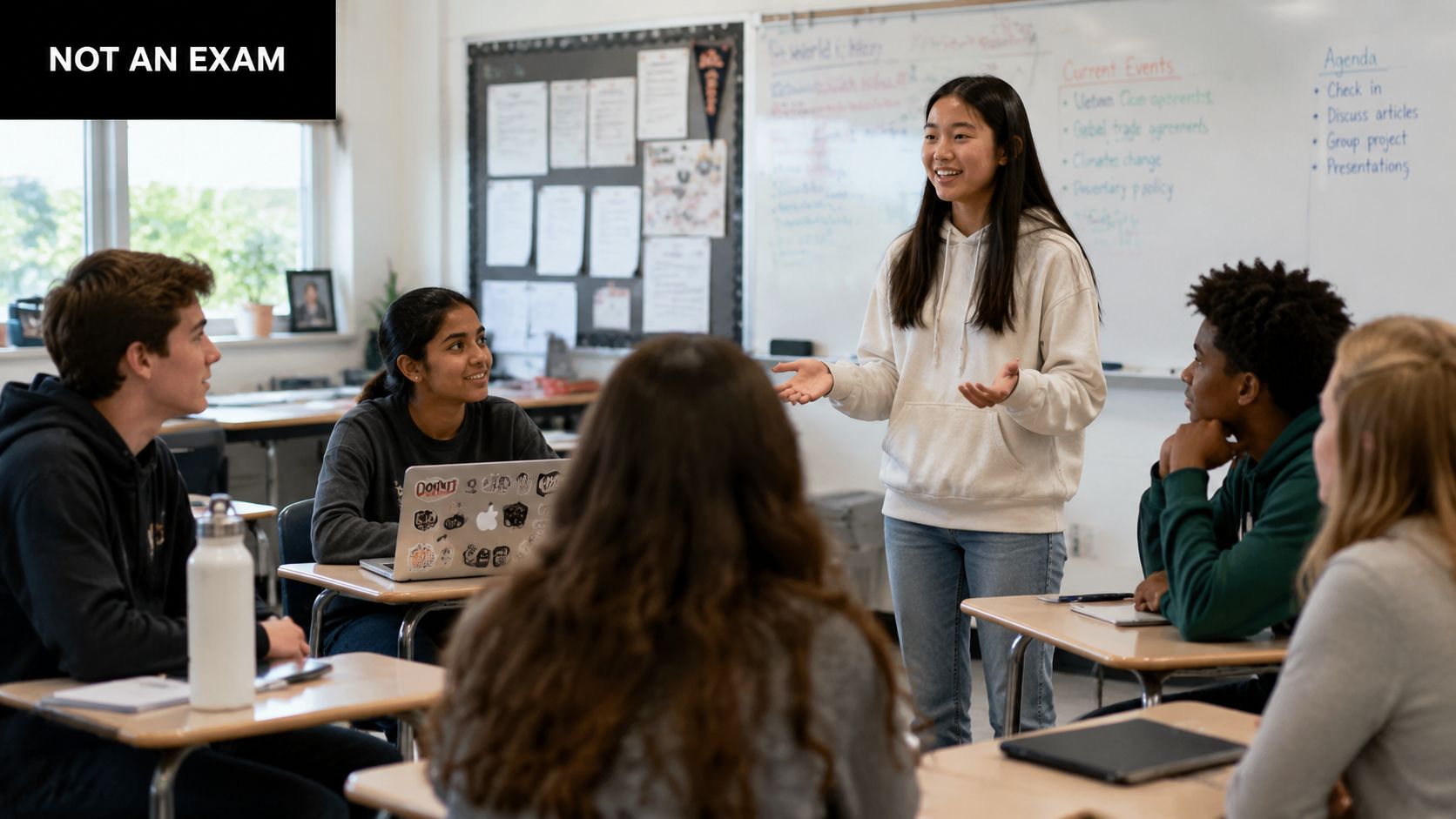 A diverse group of students in a classroom listening to a classmate give a presentation.